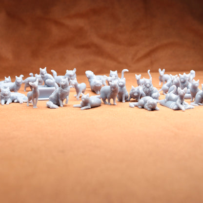 grey miniature resin cat figures on a brown background.