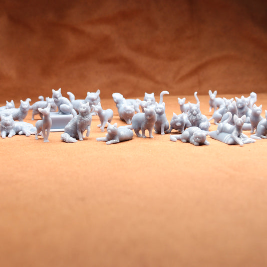 grey miniature resin cat figures on a brown background.
