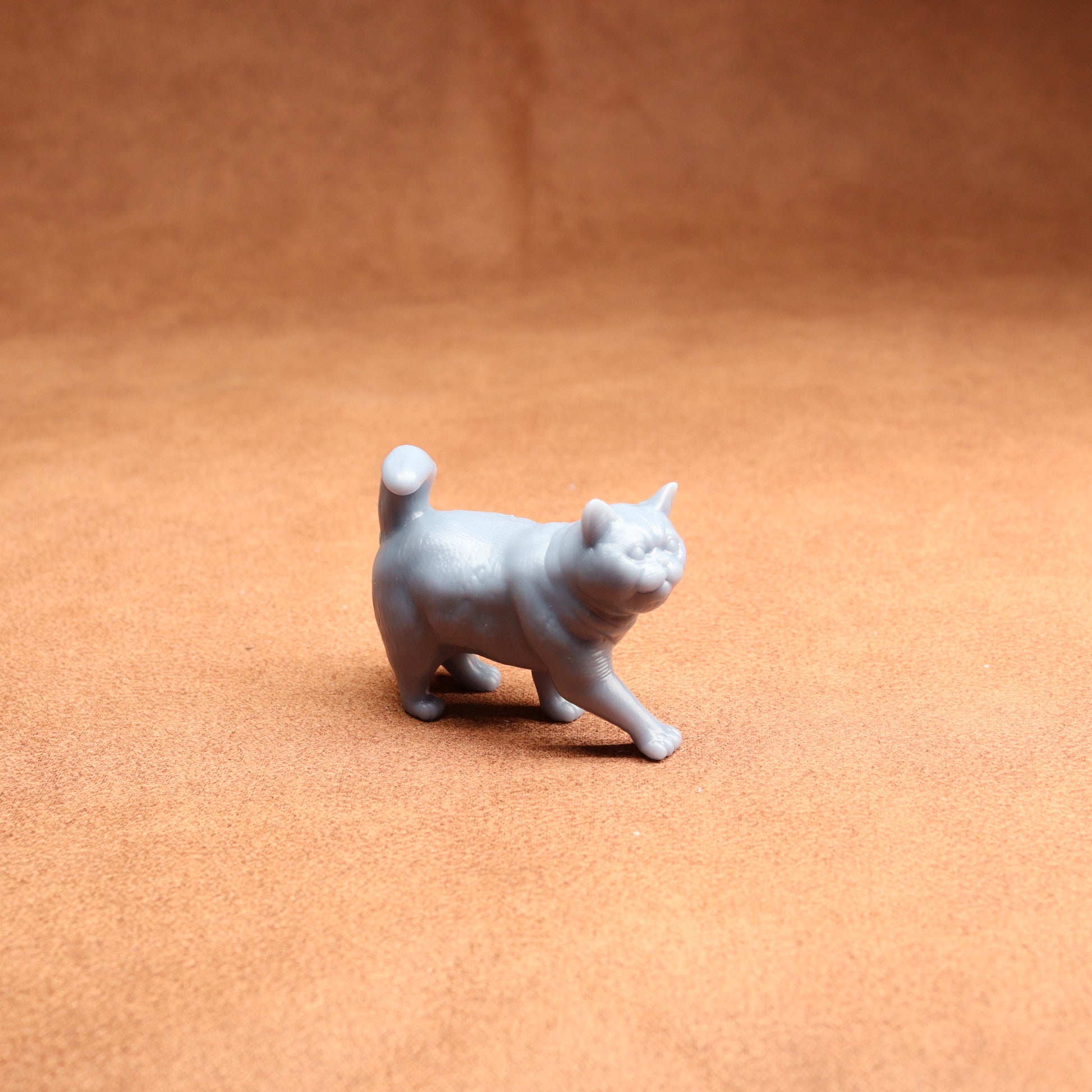 Gray cat figurine on a brown surface