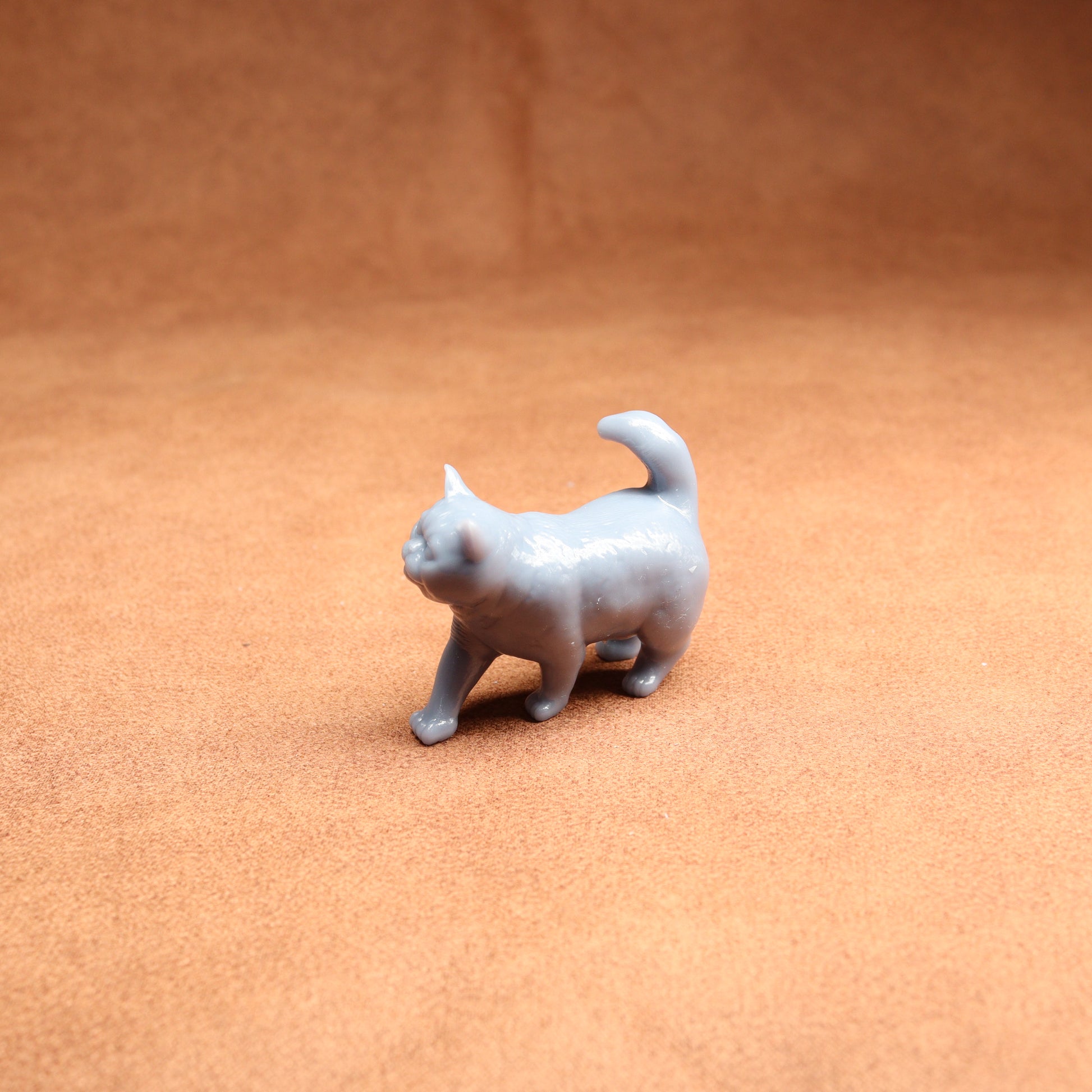 Small gray cat figurine on a brown surface