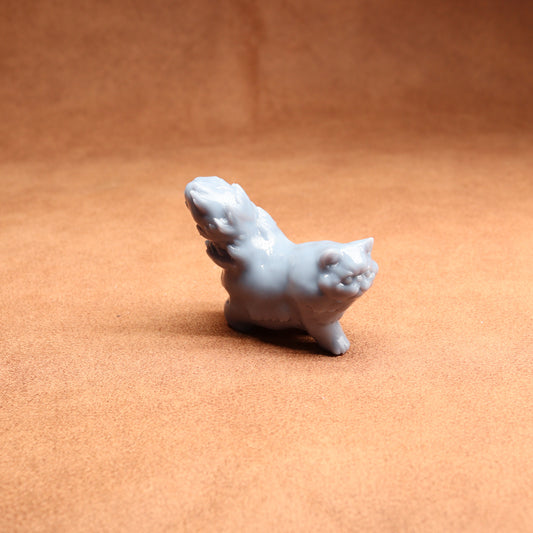 White ceramic cat figurine on a brown surface