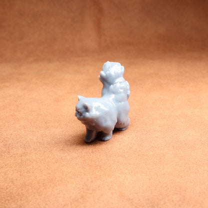 Small white ceramic dog figurine on a brown surface