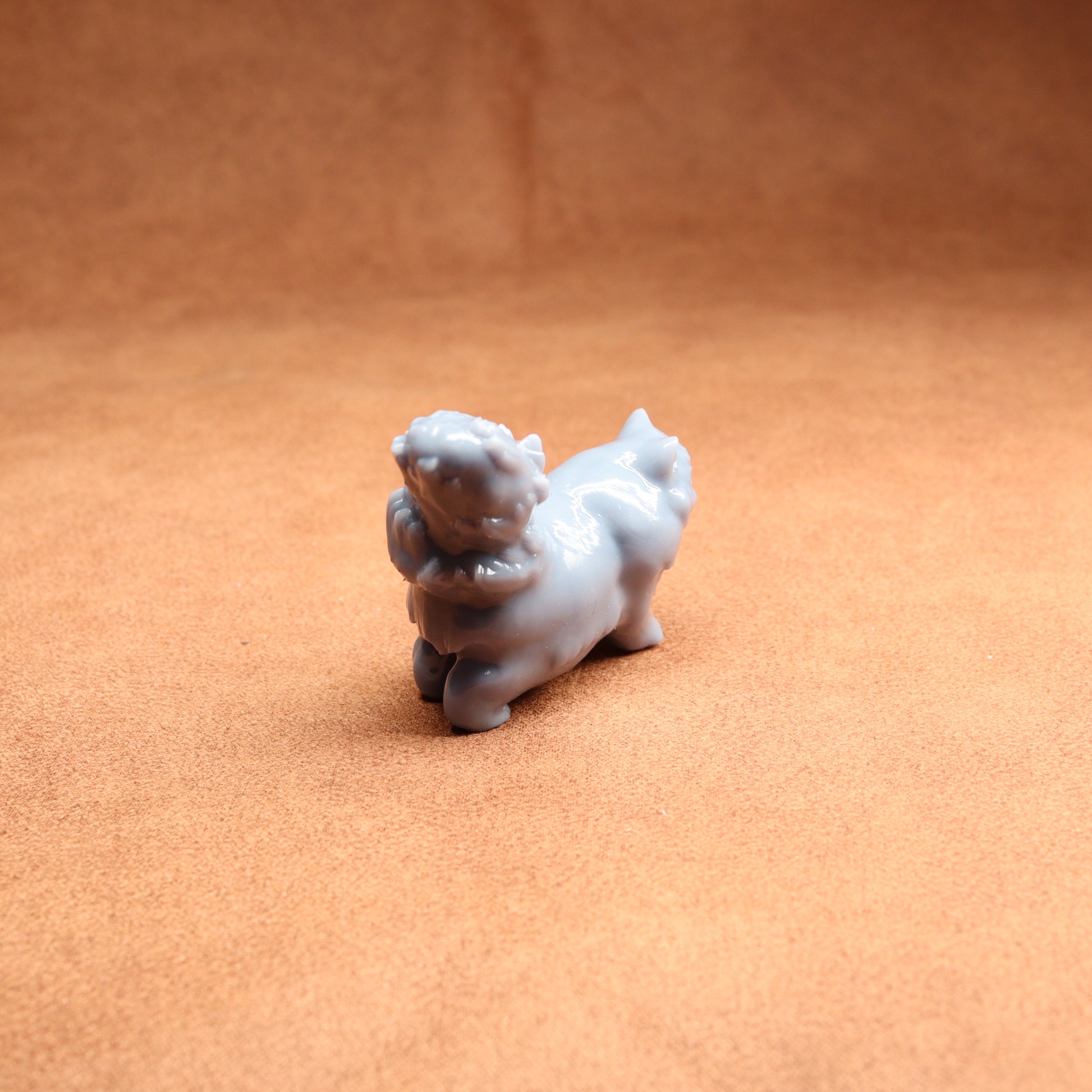 Small white figurine of a dog on a brown surface