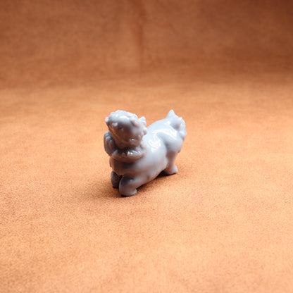 Small white figurine of a dog on a brown surface