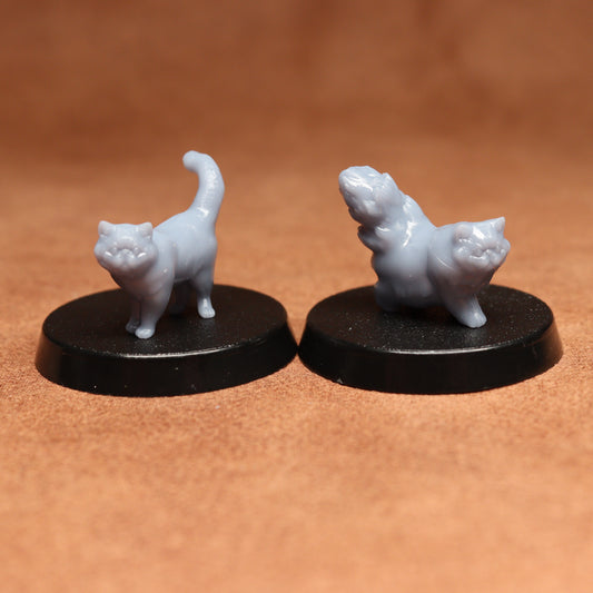 Two white cat figurines on black bases against a brown background