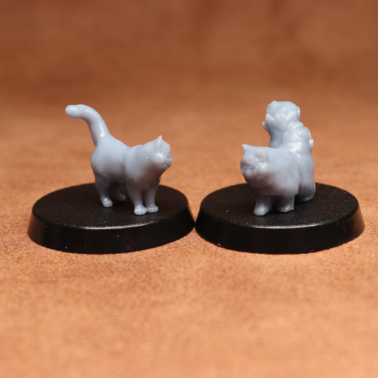 Two small white cat figurines on black bases against a brown background