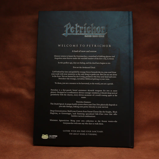 A black printed welcome sign for Petrichor, featuring white and blue text with a small green logo at the bottom, photographed against a dark brown wooden background.