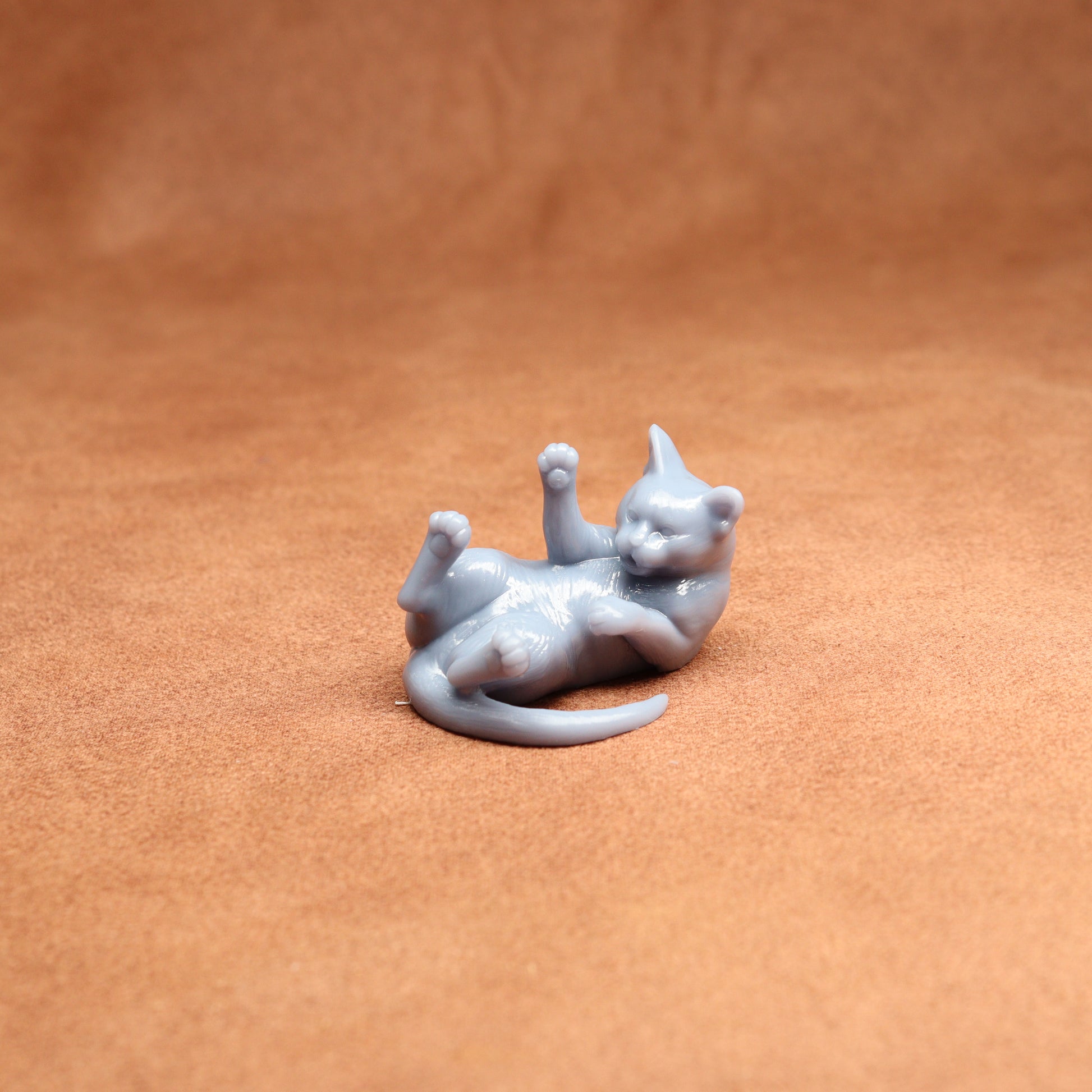 Gray cat figurine lying on a brown surface