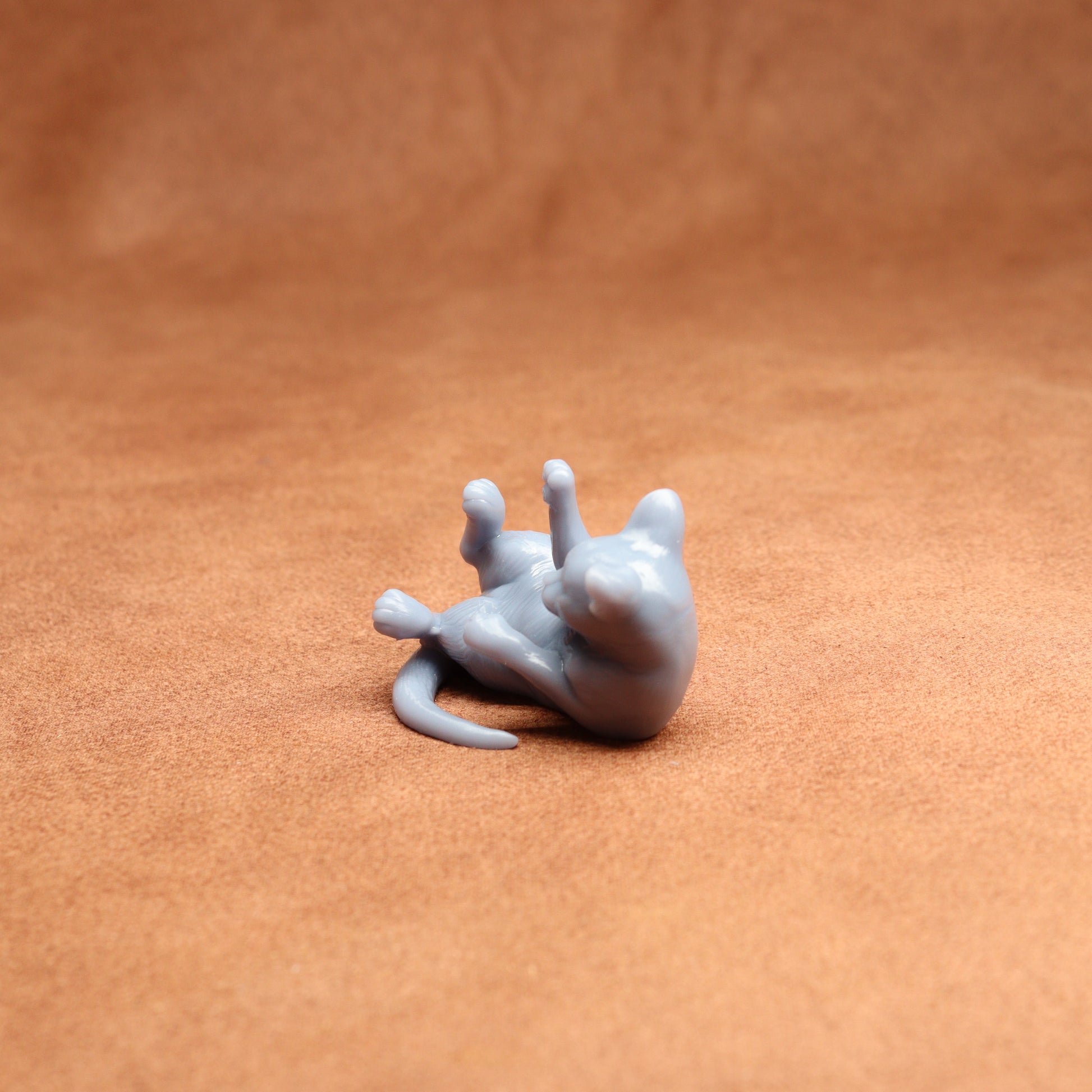 Small gray 3D-printed figure of a cat on a brown surface