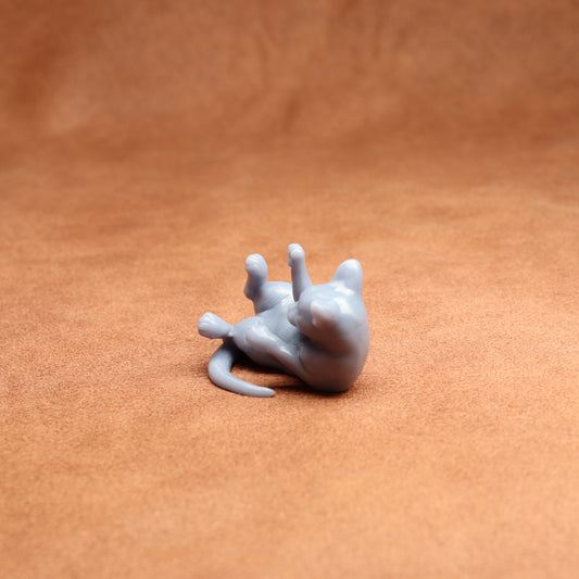 Small gray 3D-printed figure of a cat on a brown surface