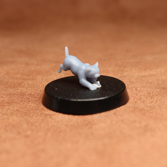 White figurine of a cat on a black round base against a brown background