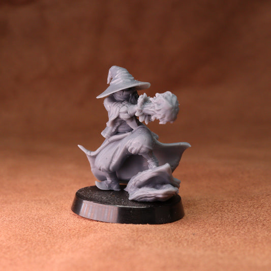 An unpainted gray fantasy miniature figurine of a wizard riding a horse, standing on a round black base against a textured brown background.