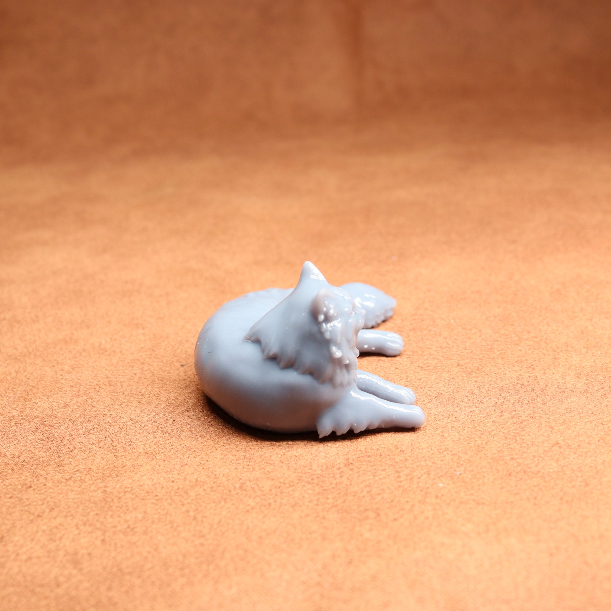 White ceramic cat figurine on a peach-colored surface