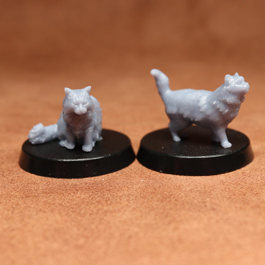Two white cat figurines on black bases against a brown background