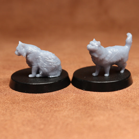 Two white cat figurines on black bases against a brown background