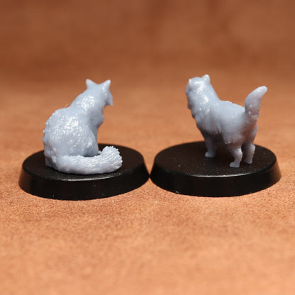 Two miniature cat figurines on black bases against a brown background