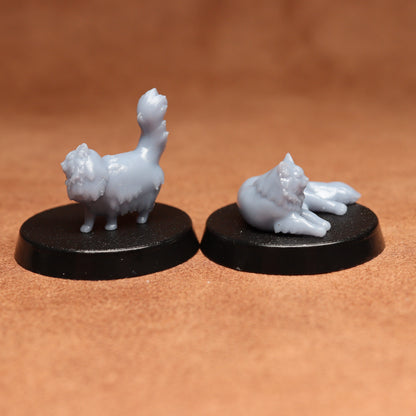 Two miniature cat figurines on black bases against a brown background