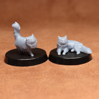 Two white cat figurines on black bases against a brown background