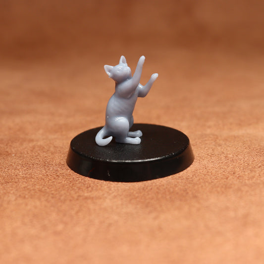 grey resin miniature cat figure on a black base with a brown background