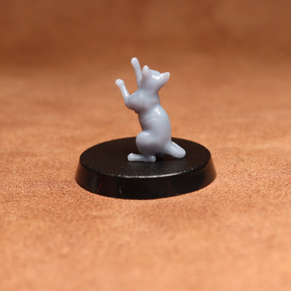grey resin miniature cat figure on a black base with a brown background