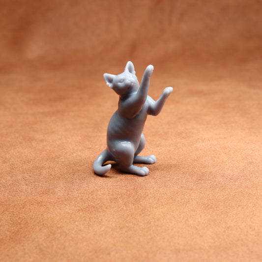 grey resin miniature cat figurine on a brown surface