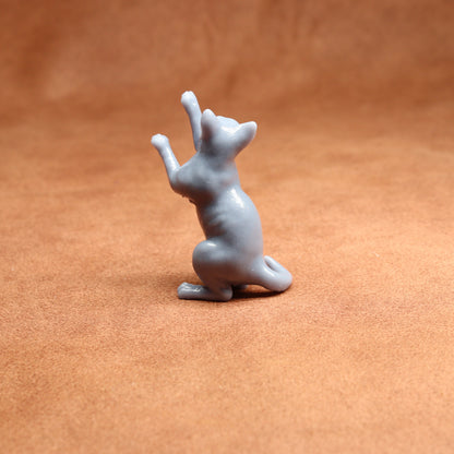 grey resin miniature cat figurine on a brown surface