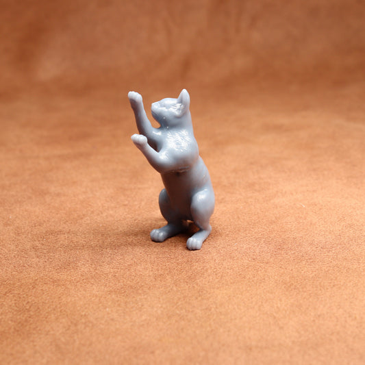grey resin miniature cat figurine on a brown surface