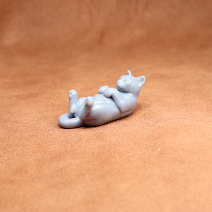 White ceramic cat figurine lying on a brown surface