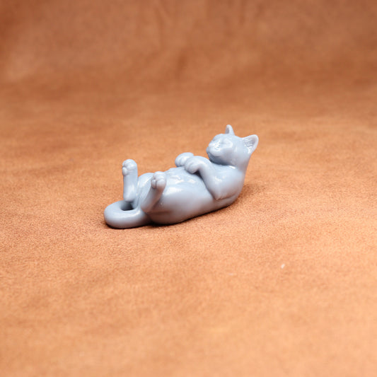 White ceramic cat figurine lying on a brown surface