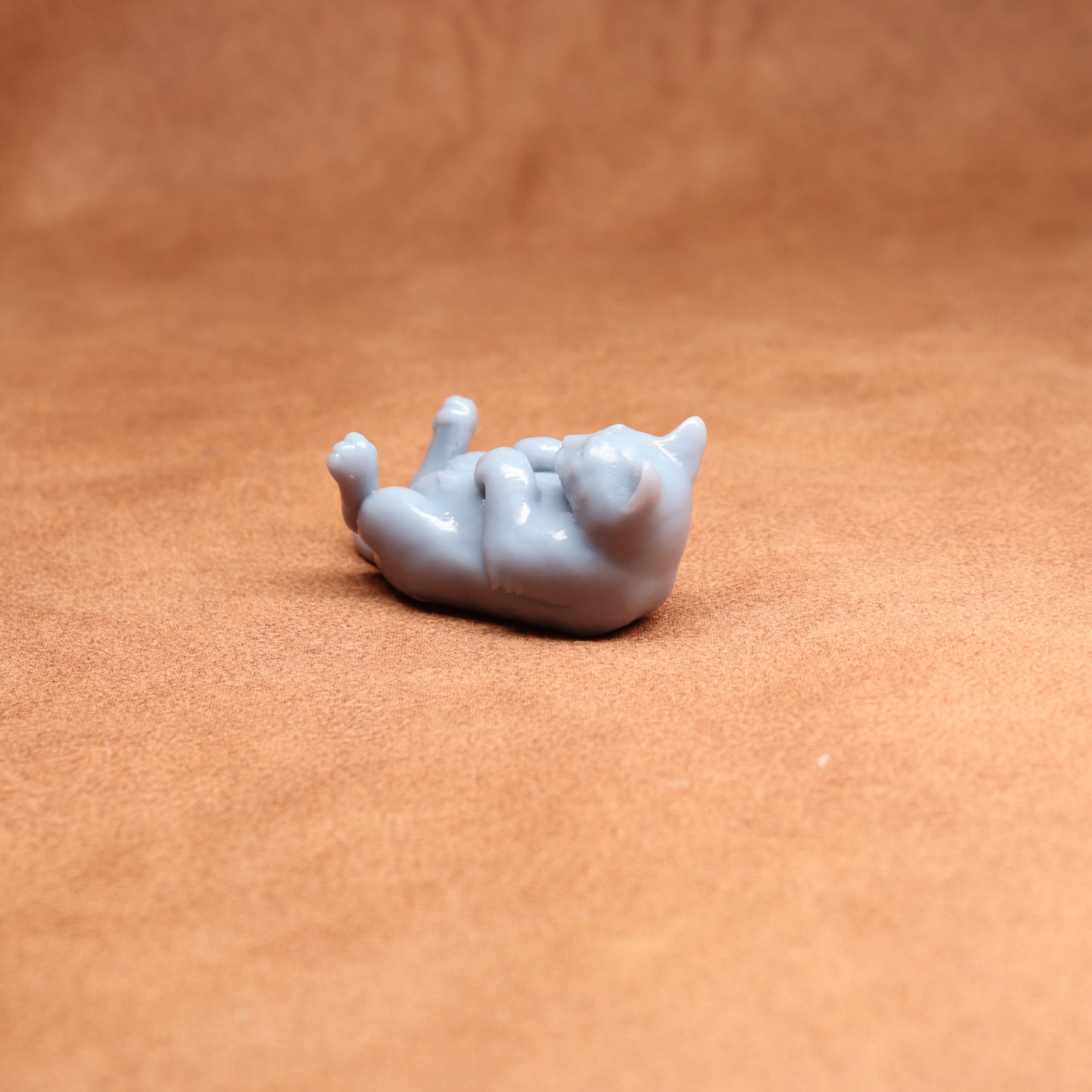 Small gray cat figurine on a brown surface