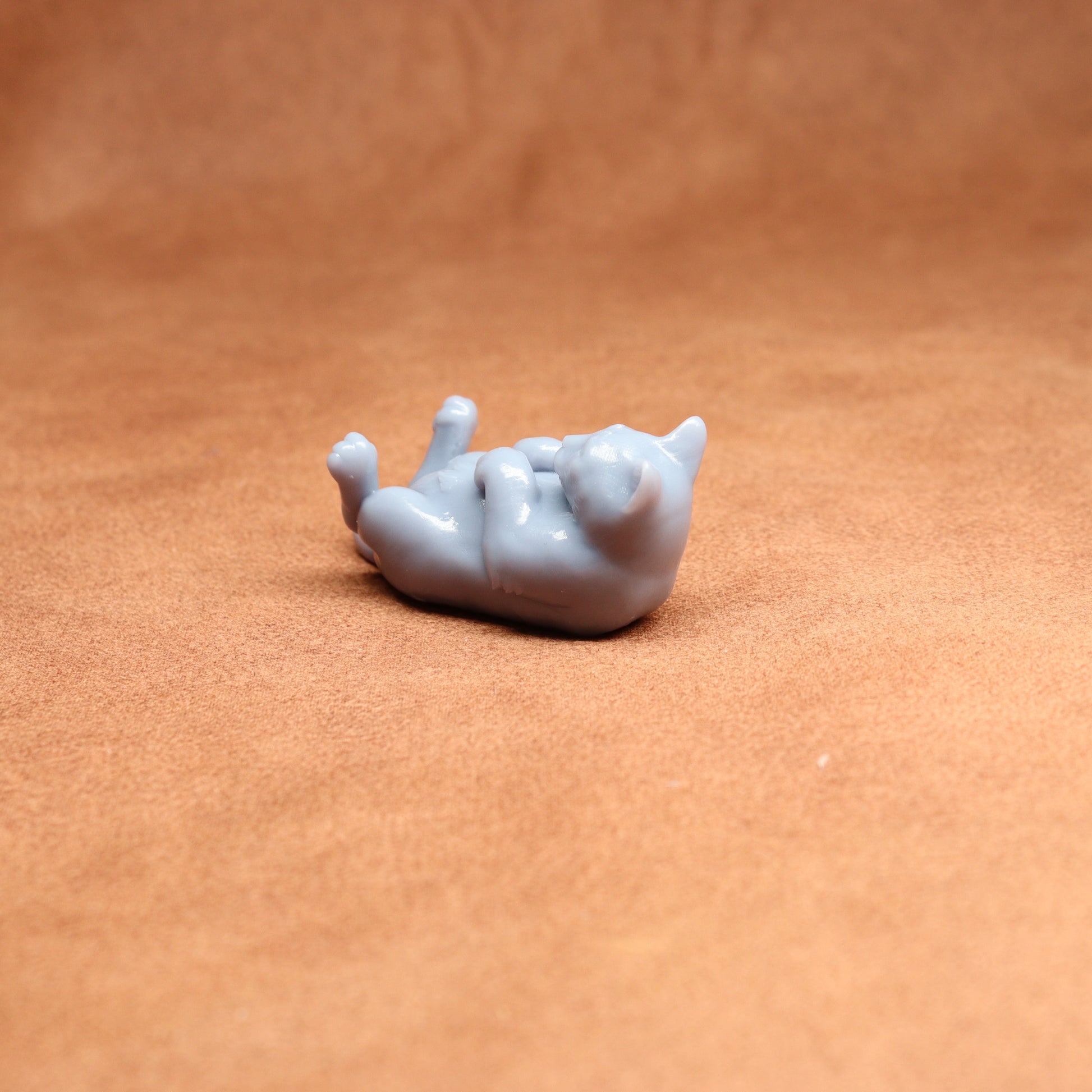 Small gray cat figurine on a brown surface