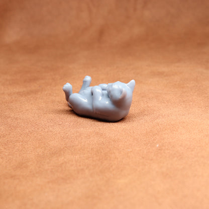 Small gray cat figurine on a brown surface