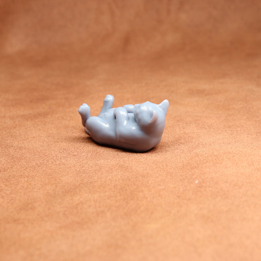 Small gray cat figurine on a brown surface