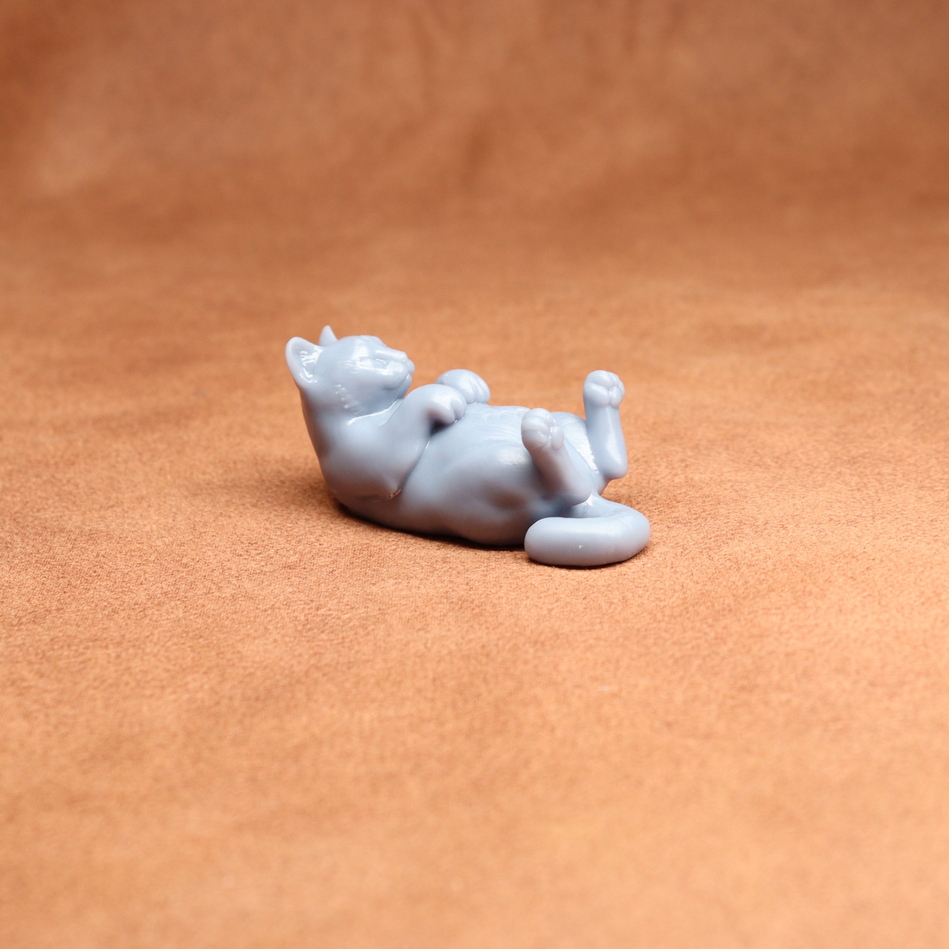 White ceramic cat figurine lying on a brown surface