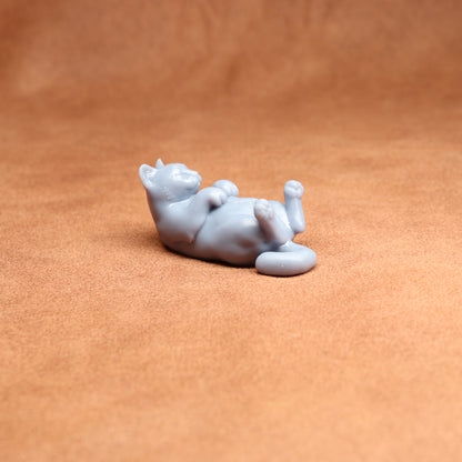 White ceramic cat figurine lying on a brown surface