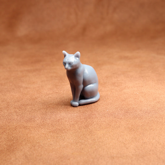 grey resin miniature cat figurine on a brown surface