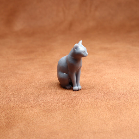 grey resin miniature cat figurine on a brown surface