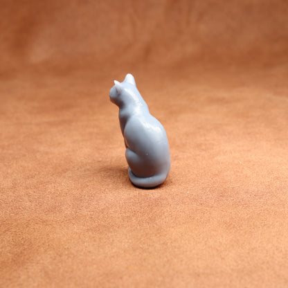 grey resin miniature cat figurine on a brown surface