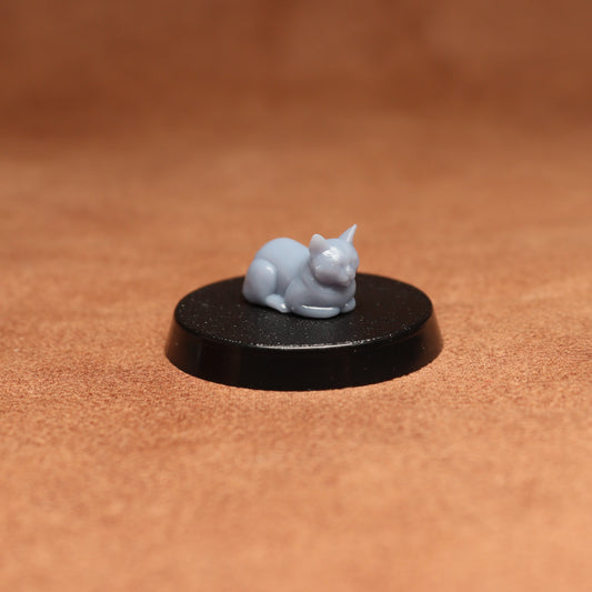 grey cat resin miniature on a black base on a brown background.