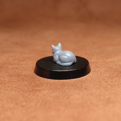 grey cat resin miniature on a black base on a brown background.