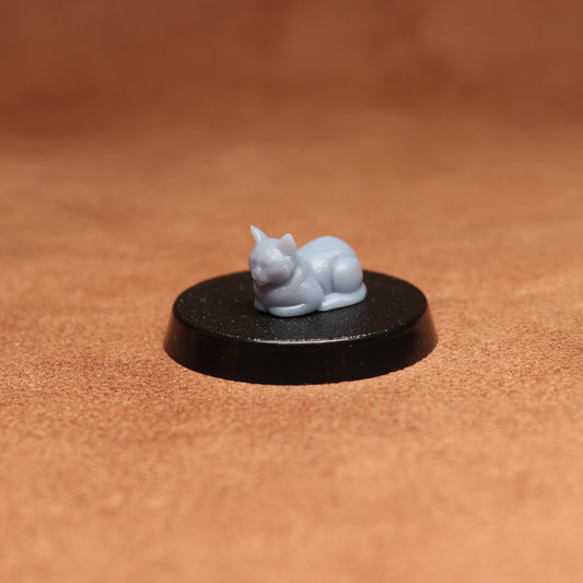 grey cat resin miniature on a black base on a brown background.