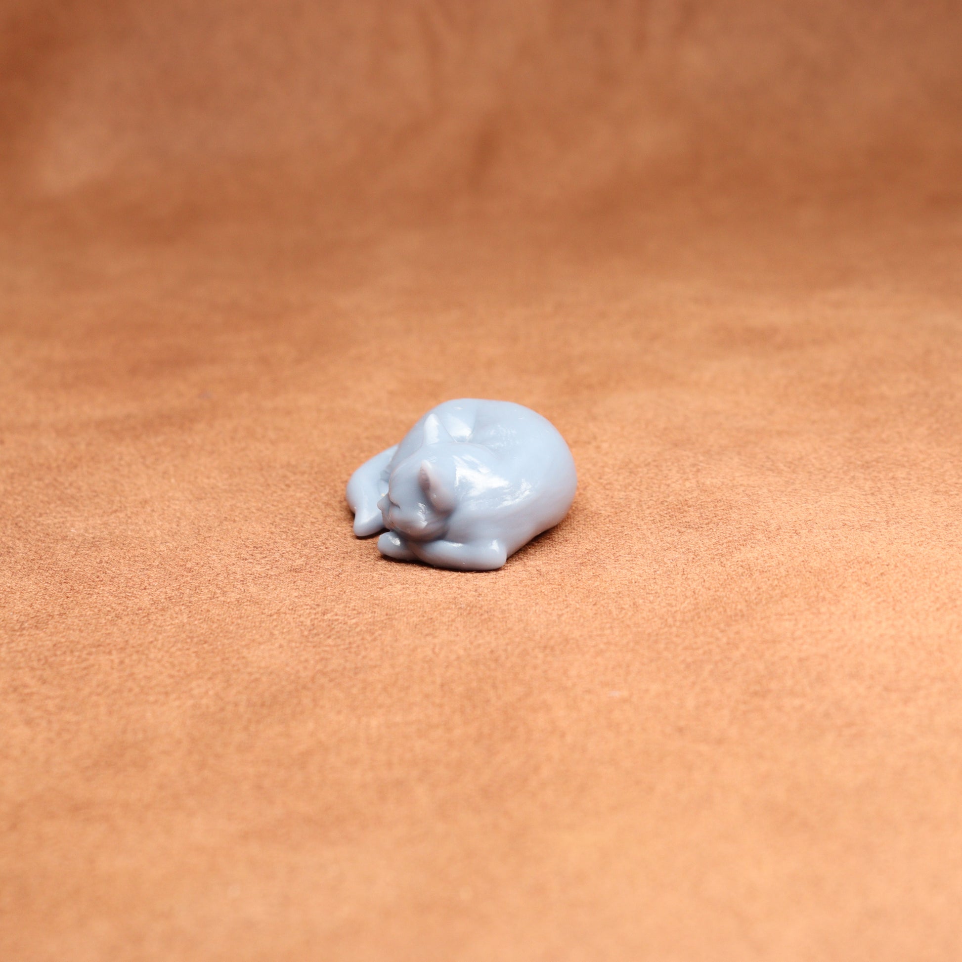 Small white resin cat figurine on a brown leather surface