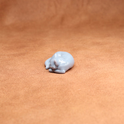Small white resin cat figurine on a brown leather surface