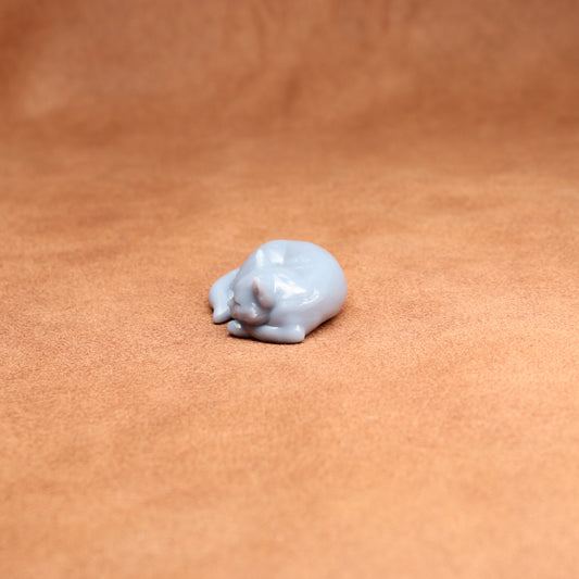 Small white resin cat figurine on a brown leather surface