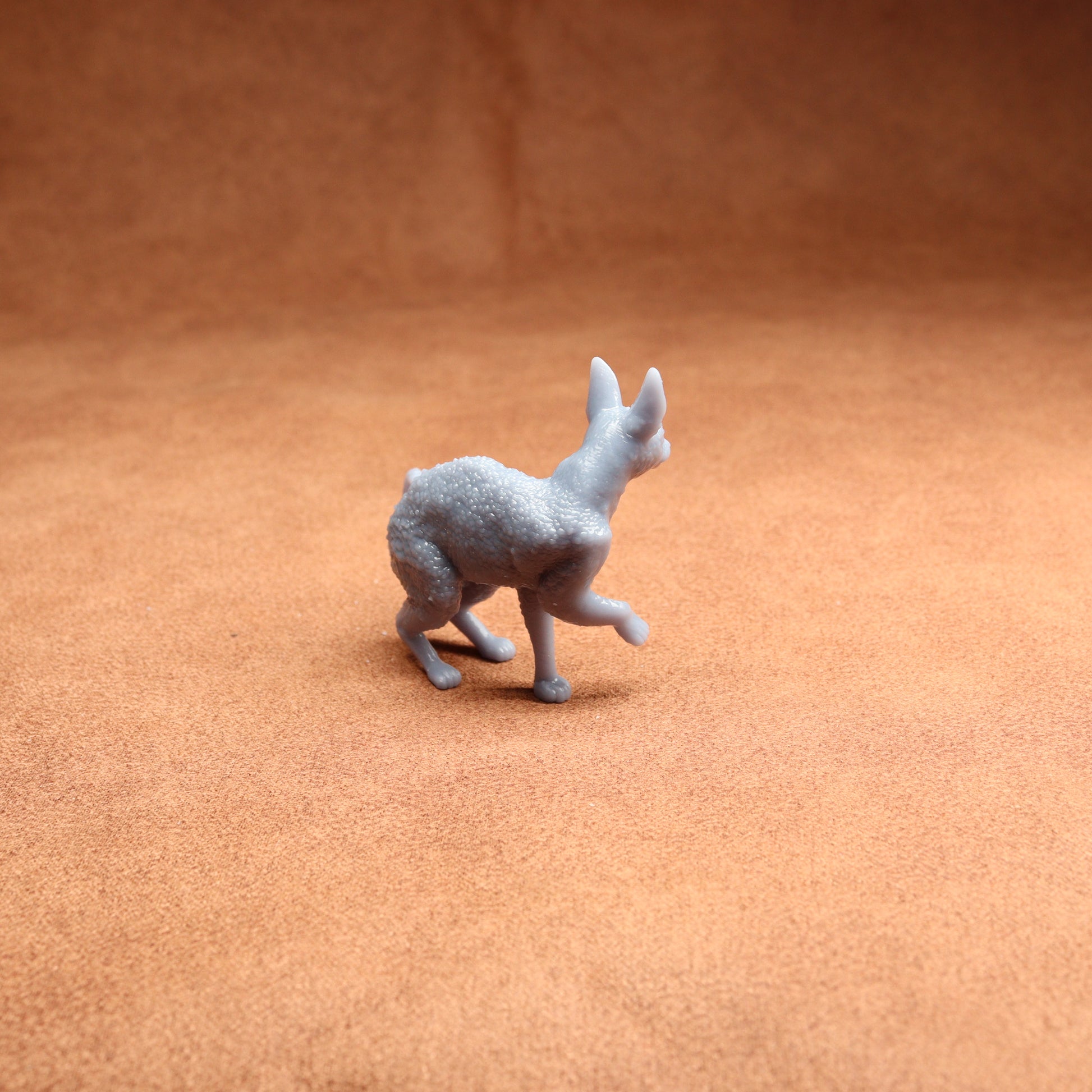 Small gray figurine of a kangaroo on a brown textured surface
