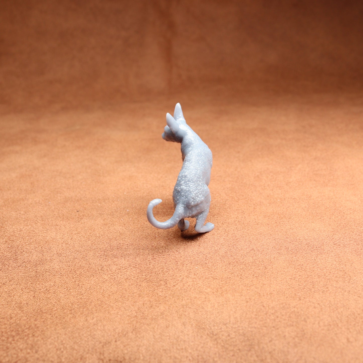 Small gray cat figurine on a brown surface