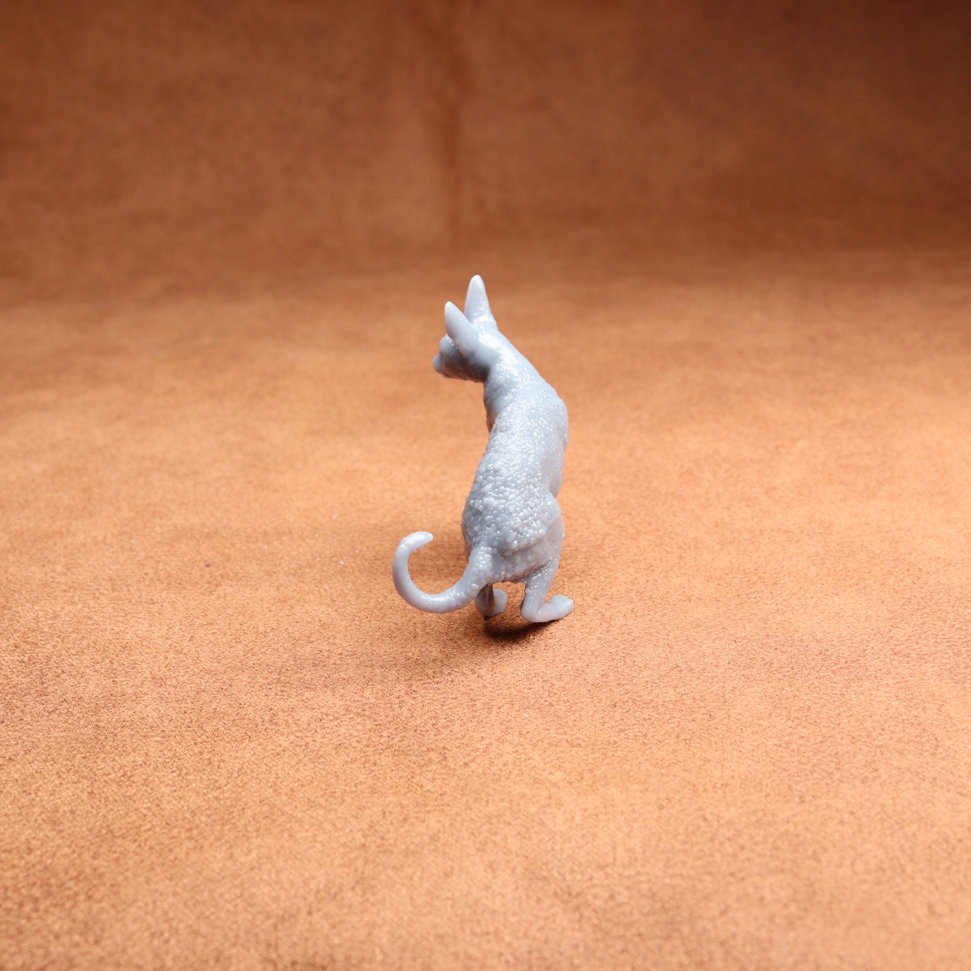 Small gray cat figurine on a brown surface
