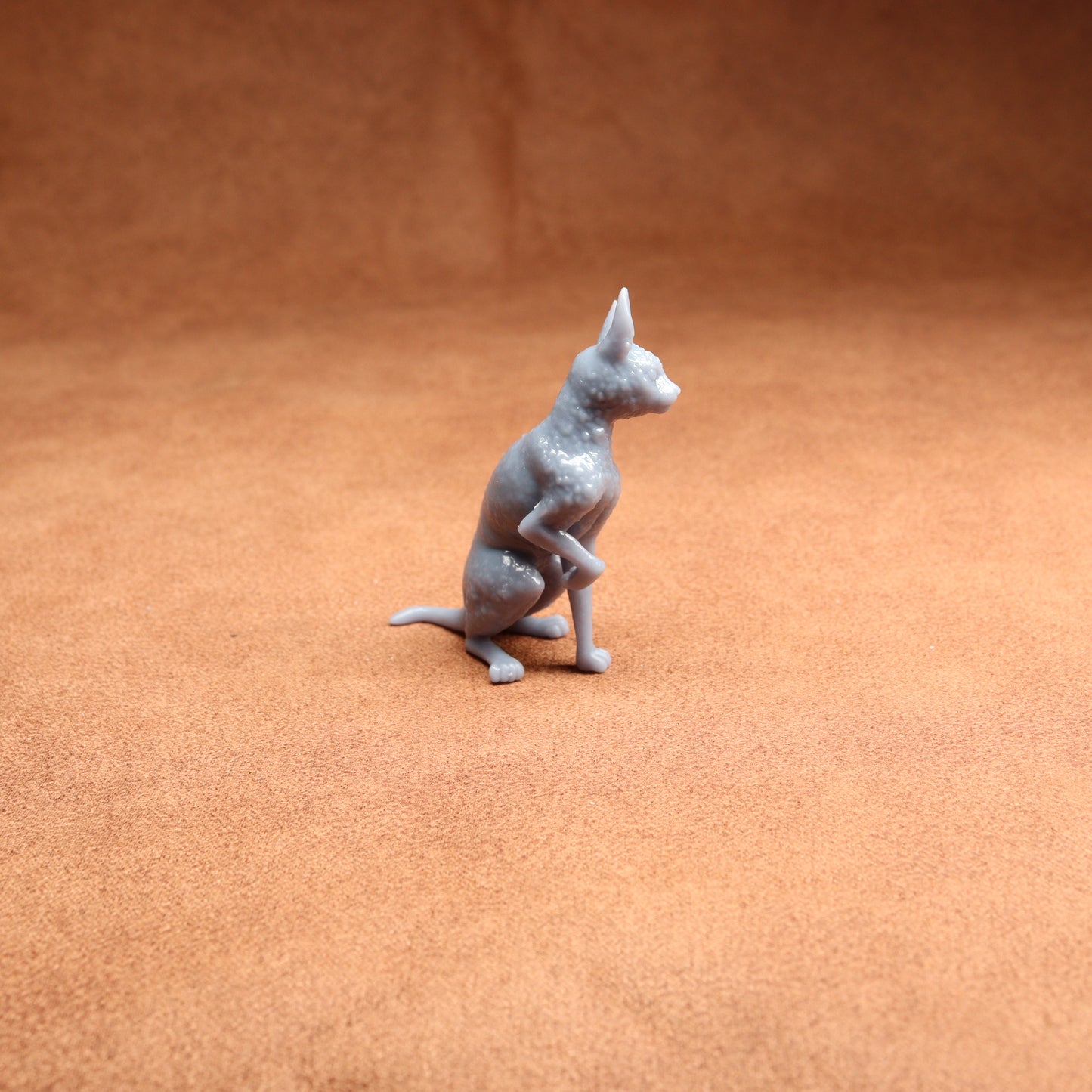 Gray cat figurine on a brown textured surface