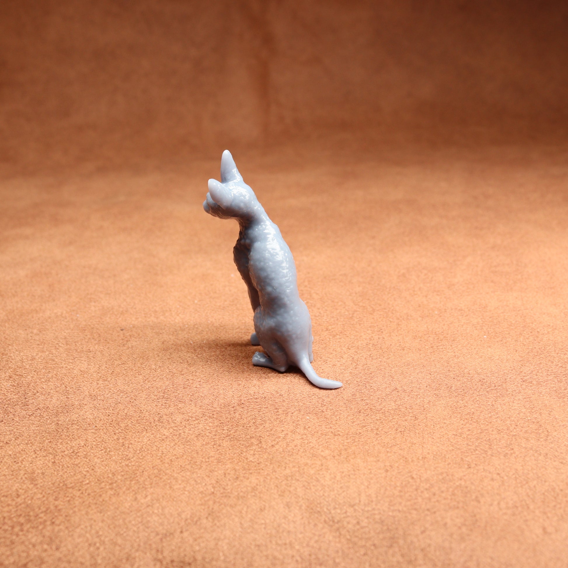 Small gray cat figurine on a brown surface