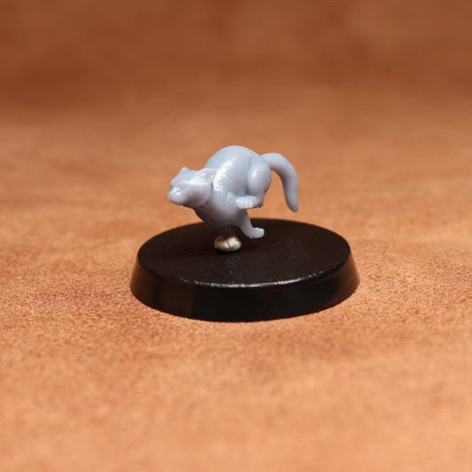 grey resin miniature cat figure on a black base with a brown background